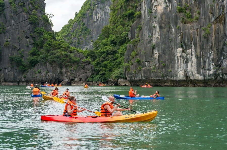 Paddling in a kayak to admire the enchanting beauty of the natural limestone mountains in Bai Tu Long Bay.